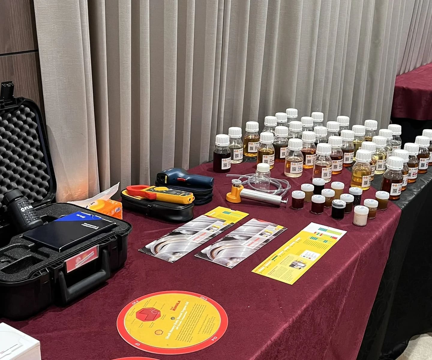 Tabel pameran botol sampel oli, peralatan teknis, dan brosur untuk demonstrasi